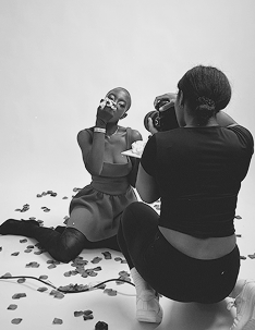 Person taking a photo of another person with a camera on a white background
